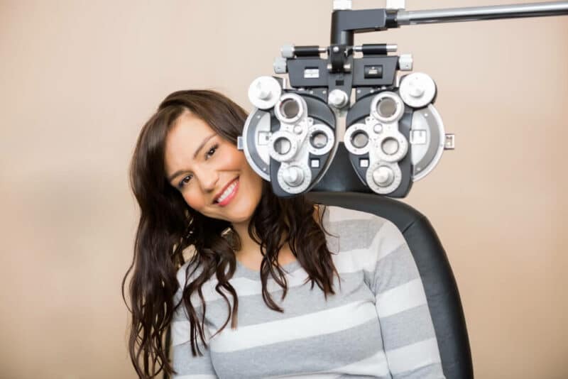 Smiling woman behind eye examination equipment