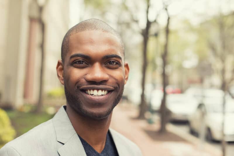 Young man smiling isolated on outside outdoors background