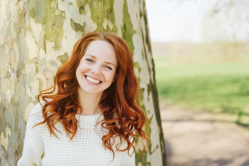 Smiling woman outside with a tree in the background